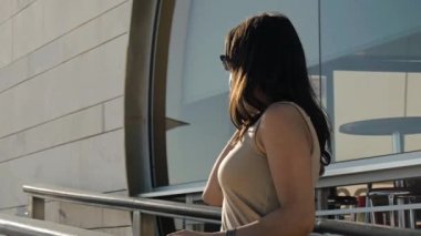 Koruyucu maskeli genç bir kadın telefonda konuşuyor.