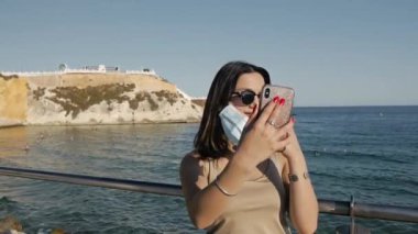 Deniz kenarındaki koruyucu maskeli genç kadın..