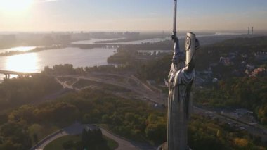 Ukrayna 'nın Kyiv kentinin havadan görünüşü, Dinyeper Nehri, köprüler, altın kubbeleri olan beyaz bir kilise ve üç çatallı mızraklı bir Ana Ukrayna anıtı..