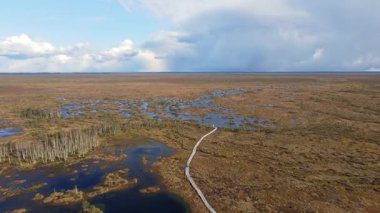 İnsansız hava aracı, Belarus 'taki Yelnya bataklığı üzerinde sorunsuzca süzülerek yağmur bulutlarıyla dolu parçalı bulutlu bir gökyüzü altında sulak alanlar, göller, kanallar ve orman adalarını ortaya çıkarıyor..