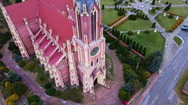 İnsansız hava aracı, Belarus köyündeki bir Neo Gotik kilisesinin, bahçelerin ve yolların yukarı doğru hareketini yakalıyor, uzaktaki tarlaları, evleri ve ormanlarıyla..
