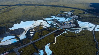 Mavi Göl 'ün sütlü mavi suları yosun kaplı lav alanları, modern spa mimarisi ve bu hava sahnesindeki dolambaçlı yollar ile tezat oluşturuyor..