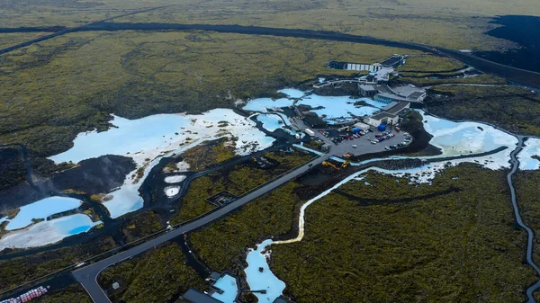 Mavi Göl 'ün sütlü mavi suları yosun kaplı lav alanları, modern spa mimarisi ve bu hava sahnesindeki dolambaçlı yollar ile tezat oluşturuyor..