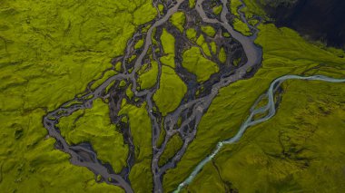 Yeşil yosunlar arasında örülmüş nehir sisteminin hava perspektifi İzlanda 'da volkanik araziyi kaplamış, kanallar ve akan su desenleriyle.