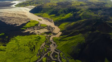 Örgülü nehir sistemi, İzlanda 'nın engebeli tepeleri ve vadileriyle çevrili yeşil yosun kaplı arazi ve karanlık volkanik topraklar boyunca akar..