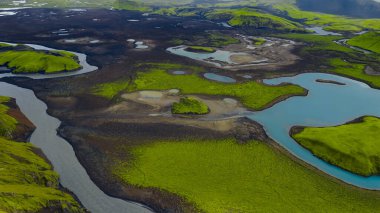 İzlanda 'nın yeşil yosunlarının hava perspektifi koyu volkanik topraklar, dolambaçlı mavi bir nehir ve dağınık su havuzlarıyla kaplıydı..