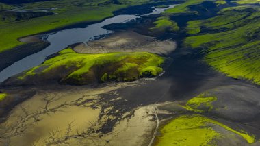İzlanda 'nın volkanik arazisinin hava perspektifi yosun kaplı tepeler, karanlık toprak ve yemyeşil ve çorak toprakları ayıran dolambaçlı bir nehir içerir..