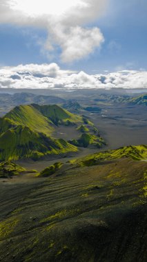 İzlanda 'nın volkanik manzara perspektifi yosun kaplı dağlar, geniş siyah kum düzlükleri ve bulutların arasından süzülen güneş ışığı..