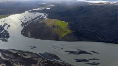 Çamurlu suları olan dolambaçlı bir nehir İzlanda 'daki volkanik bir arazide akar, yeşil bir yarımadayla çelişir ve karmaşık doğal desenler ortaya çıkar..