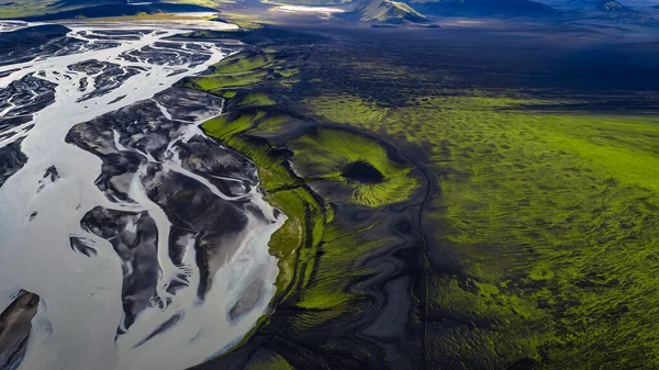 İpeksi suyla örülmüş nehir, yeşil yosun ve dağlarla çevrili karanlık volkanik arazide akar. Yumuşak, dağınık ışık altında..