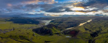 Yeşil yosun kaplı tepeler, kırmızımsı volkanik bir sırt ve İzlanda 'daki karanlık bir volkanik ovada akan örülmüş bir nehir sistemi..