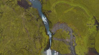 İnsansız hava aracı canlı mavi bir nehir yakalıyor. Beyaz akıntılar yosunlu volkanik araziyi kesiyor. Dinamik hareketler ve eşsiz yer dokuları sergiliyor..