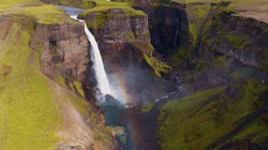 İnsansız hava aracı, yüksek bir şelaleyi yakalar yemyeşil uçurumlarla dolu bir kanyona düşer, sis yükselir ve İzlanda 'nın engebeli arazisinde bir nehir kıvrılır..
