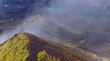 İzlanda 'nın engebeli volkanik arazisinin havadan görünüşü, yosun kaplı tepeler, küllerle kaplı yamaçlar ve hareketli volkanik tozlar.