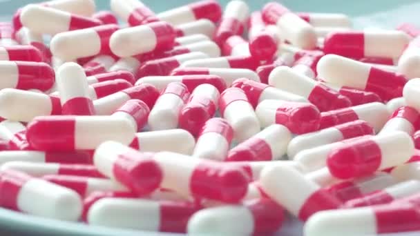 Červeno bílé pilulky otočit na modrou desku makro snímek — Stock video