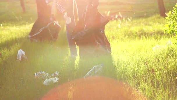 Duas meninas voluntários camisas ao pôr do sol com lixo, close up slow mo — Vídeo de Stock