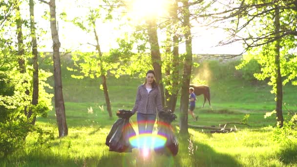 Meisje vrijwilliger in shirt met plastic vuilniszakken in het Park, Sunny — Stockvideo