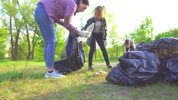 Moeder en tiener dochter verzamelen vuilnis in plastic zakken in park concept — Stockvideo