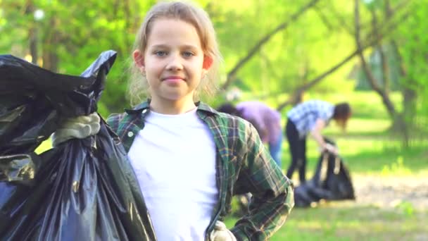 Portrait d'un adolescent volontaire avec un sac en plastique avec des ordures dans les mains en regardant la caméra — Video