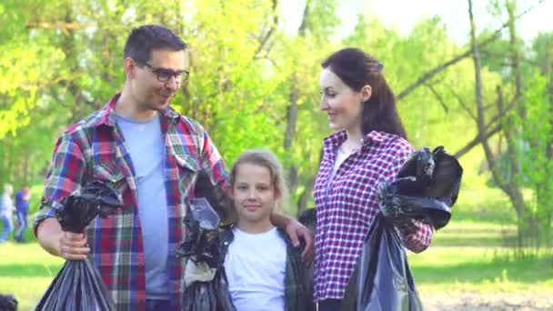 Портрет молодої дівчини добровольця-підлітка і молодого хлопця з поліетиленовим пакетом зі сміттям в руках — стокове відео