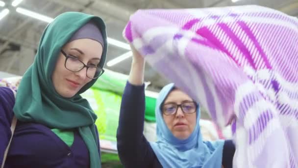 Zwei schöne muslimische Frauen beim Einkaufen, wählen Sie Textilien aus nächster Nähe — Stockvideo