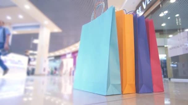 Barva balíčky pro nakupování v nákupním středisku na pozadí lidí, close-up — Stock video