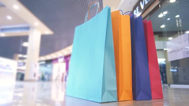 Цветные сумки в торговом центре на фоне проходящих людей, Timelapse — стоковое видео