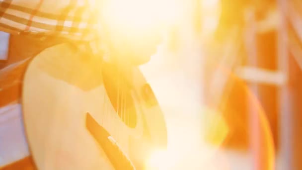 Неузнаваемые руки девушка в рубашке уличный музыкант играет на гитаре на закате — стоковое видео
