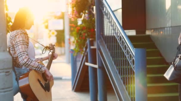Straat muzikant meisje gitaarspelen bij zonsondergang, langzame mo — Stockvideo