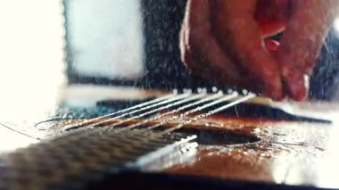 Gitar dizeleri yağmurda sprey ile mızrap yumruk