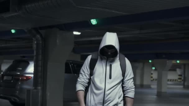 Man criminal in the balaclava and the hood in the underground parking — Stock Video