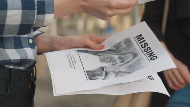 Menina distribuindo folhetos sobre a criança desaparecida, close up slow mo — Vídeo de Stock