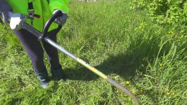 Trabajador en overoles segando la podadora de hierba alta — Vídeo de stock