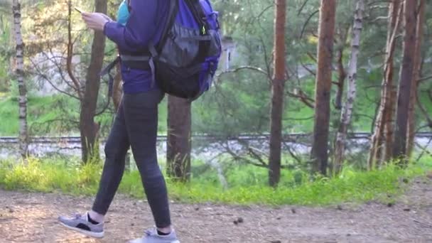 Девушка туристка с рюкзаком и есть телефон, солнце вспышки Gimbal выстрел — стоковое видео