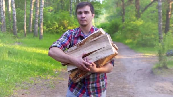 Retrato de un hombre en una camisa que lleva madera astillas troncos de abedul lento mo — Vídeo de stock