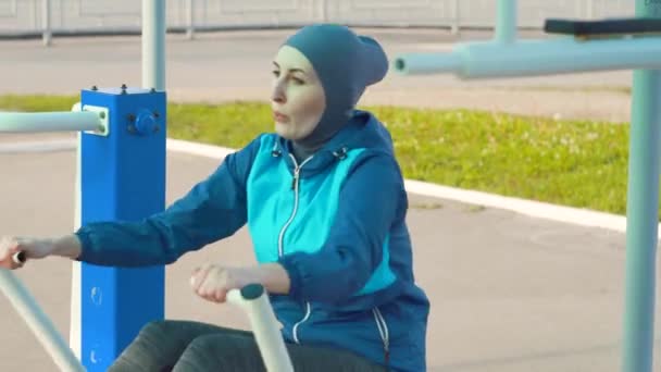 Девушка в хиджабе на тренажерных залах для гребли — стоковое видео