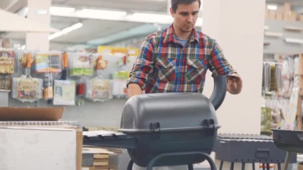 Tipo en la camisa a cuadros está mirando a la tienda de la parrilla — Vídeos de Stock