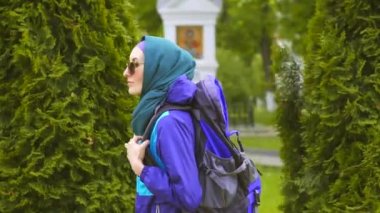 sevimli kadın turist hijab ve güneş gözlüğü ile parkta yürüyüş sırt çantası