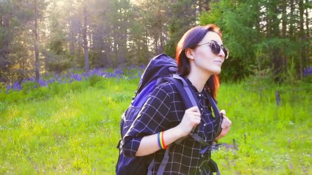 Retrato de una chica con gafas excursionista con una mochila que va en el bosque — Vídeos de Stock