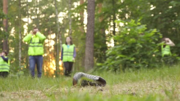 Rescatistas en chalecos verdes, encontraron las zapatillas de deporte de personas desaparecidas, están en el camino — Vídeo de stock