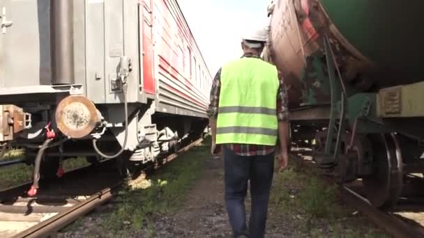 Spoorweg werknemer gaat langs de trein met een cheque — Stockvideo