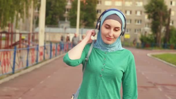 Junge muslimische Sportlerin mit Rucksack auf der Leichtathletikbahn — Stockvideo