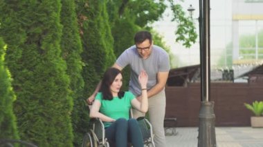 Genç adam, tekerlekli sandalyede bir engelli kız yürümek
