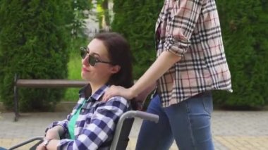 kız sokakta tekerlekli sandalyeli Engelli bir kişi yardımcı olur.