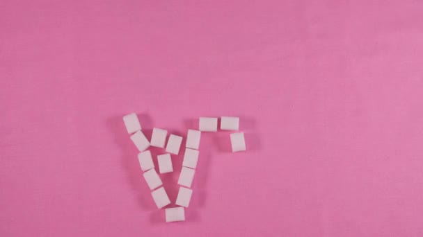 Een ongezonde tand met cariës is bekleed met geraffineerde suiker kubussen op een roze achtergrond. — Stockvideo