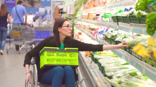 Женщина с инвалидностью в инвалидной коляске выбирает товары в магазинах в supermarket.close до — стоковое видео
