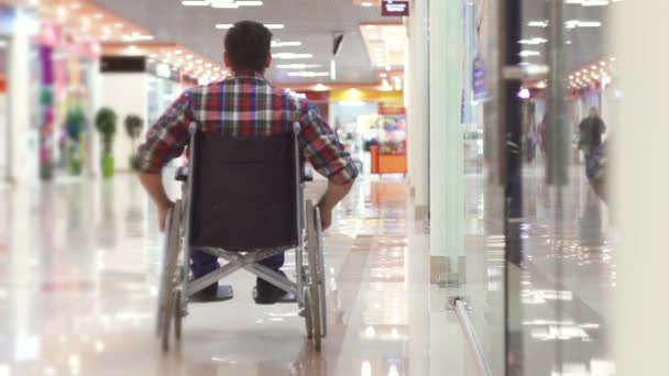 Homem com uma deficiência em uma cadeira de rodas indo para o shopping — Vídeo de Stock