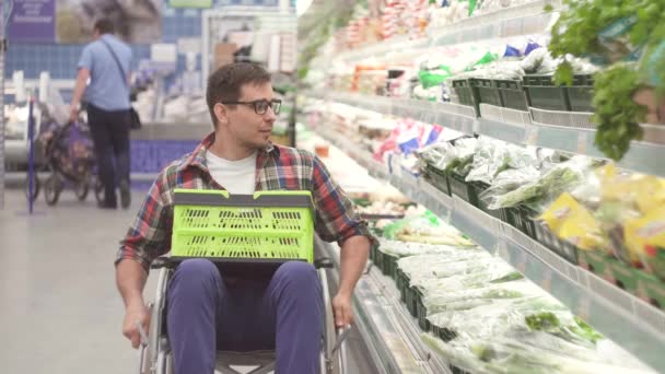 Человек с инвалидностью в инвалидной коляске выбирает товары в магазинах в супермаркете крупным планом — стоковое видео