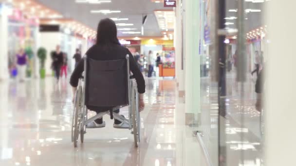 Жінка з інвалідністю в інвалідному візку йде до торгового центру — стокове відео