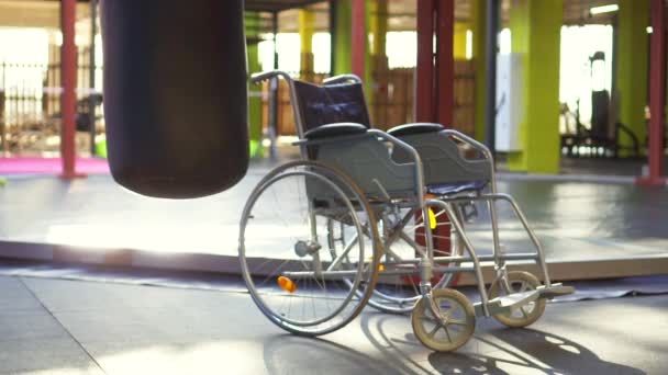 Una silla de ruedas está en el gimnasio.El concepto de lesión deportiva. — Vídeo de stock